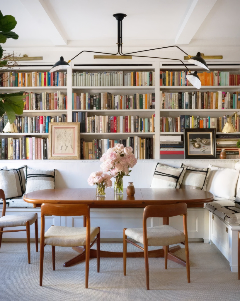 Cozy dining library interior design with dining table, wall bookshelves and warm lighting