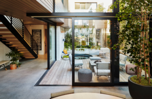 modern home courtyard with glass doors, indoor outdoor seating, greenery, and private patio design