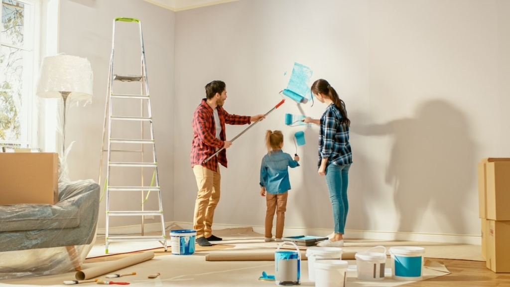 Family painting interior wall as part of DIY home renovation, showing budget-friendly upgrade and improve don’t move strategy
