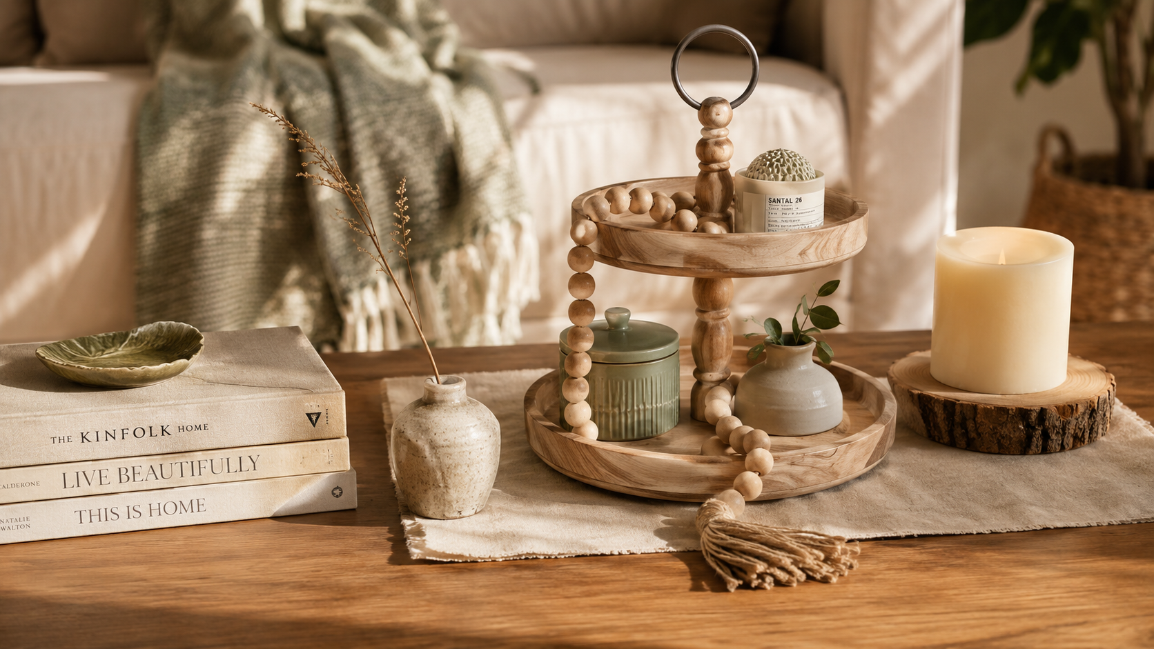 Natural wood bead garland draped across a linen tray styled with ceramic vase and books on a warm wooden coffee table