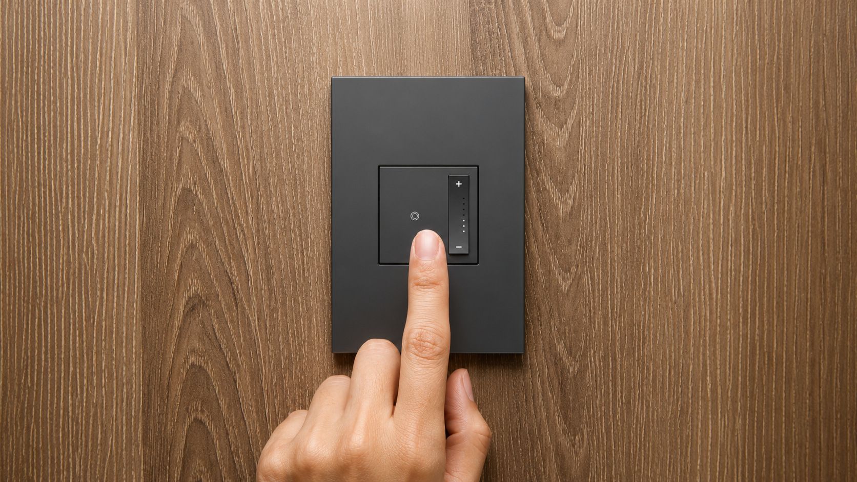 Hand adjusting an in-wall dimmer switch with warm lamp glow behind