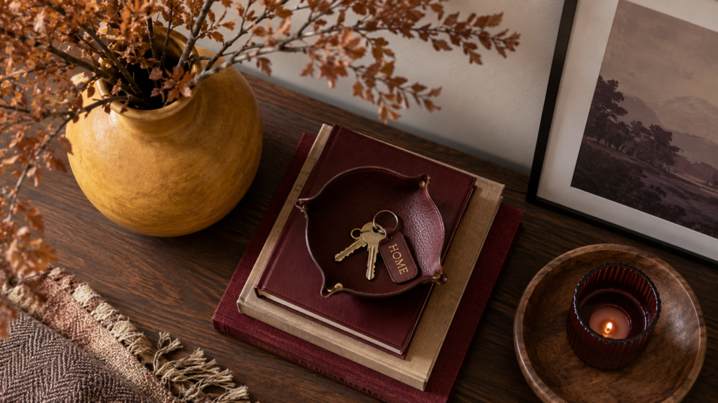 Overhead styling shot of a mustard vase, burgundy books, and oxblood leather dish on an entryway table